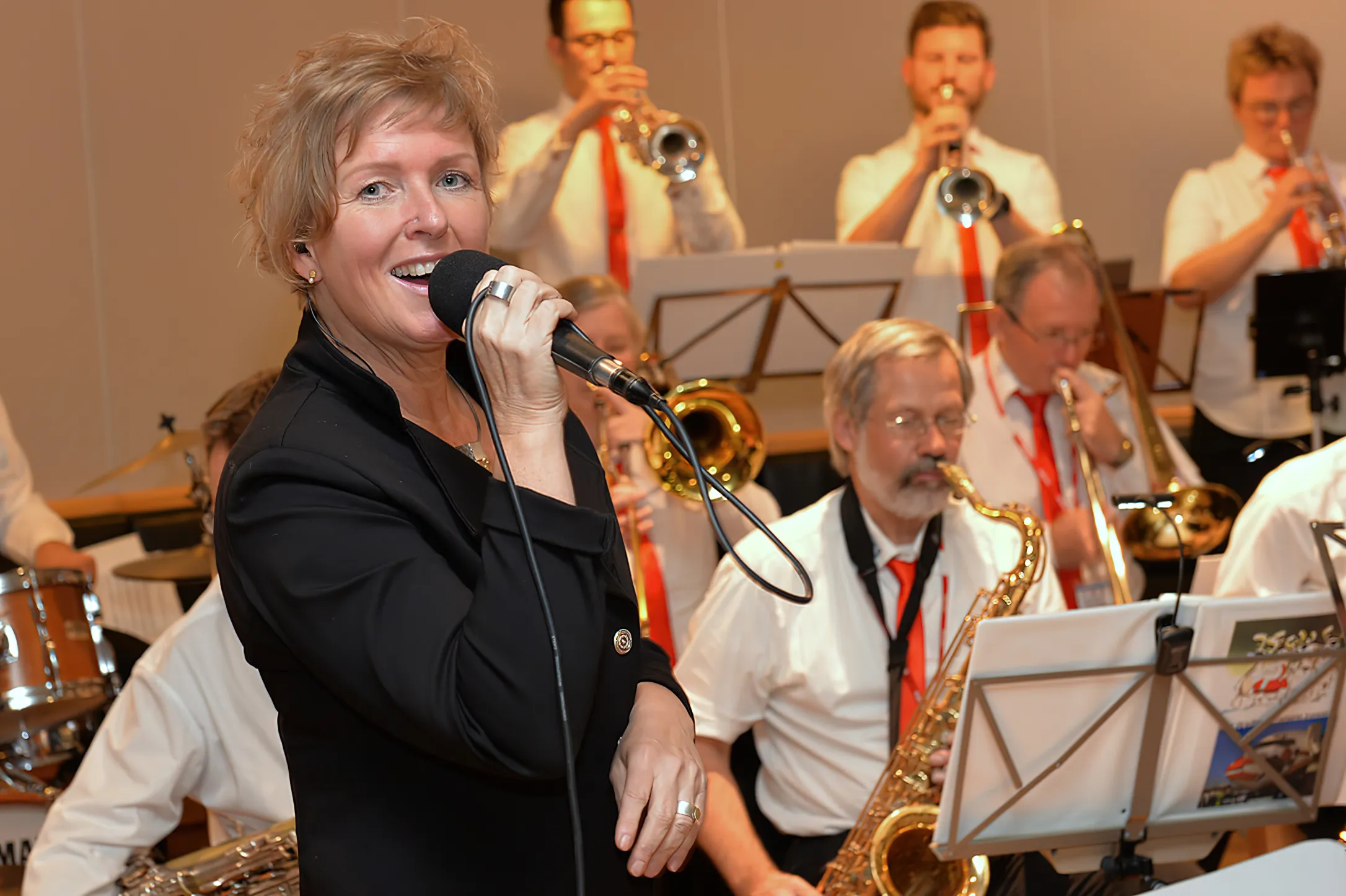 Andrea Betche singt vor einer Big Band mit Trompeten- und Saxofonsatz