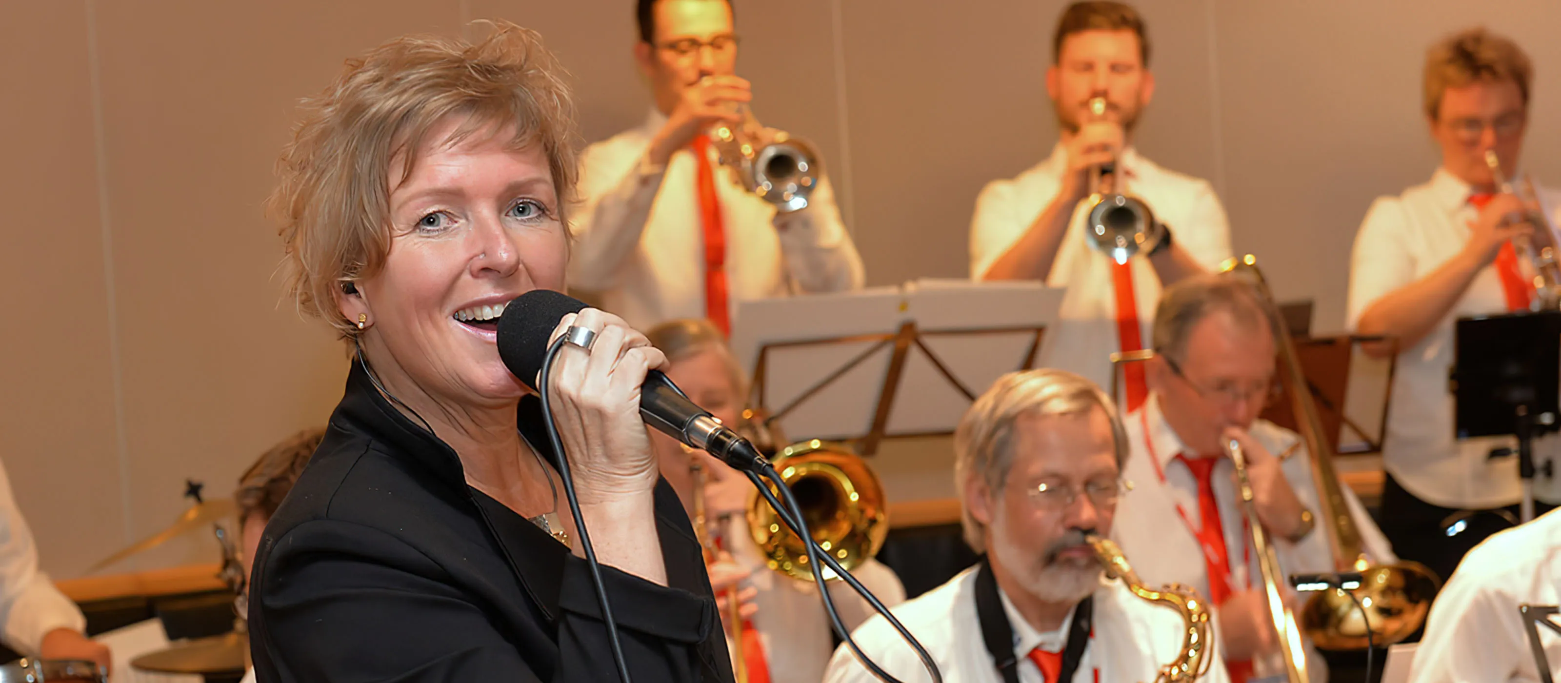 Andrea Betche singt vor einer Big Band mit Trompeten- und Saxofonsatz